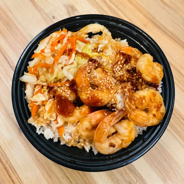 Shrimp teriyaki bowl with white rice, stir-fried cabbage, carrots, and sesame seeds.