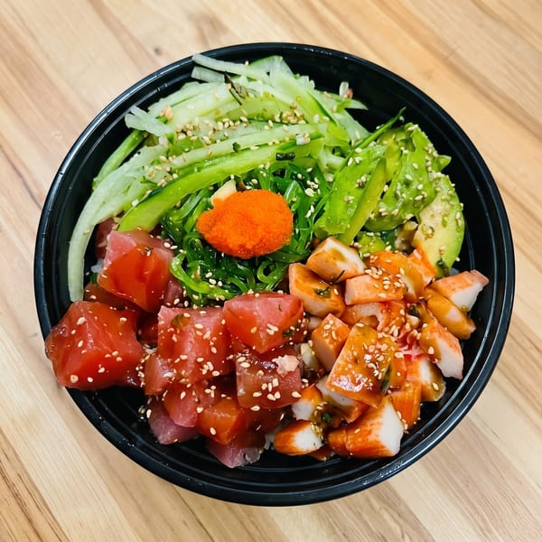 A vibrant poke bowl with tuna, crab, avocado, seaweed salad, cucumber, and roe.